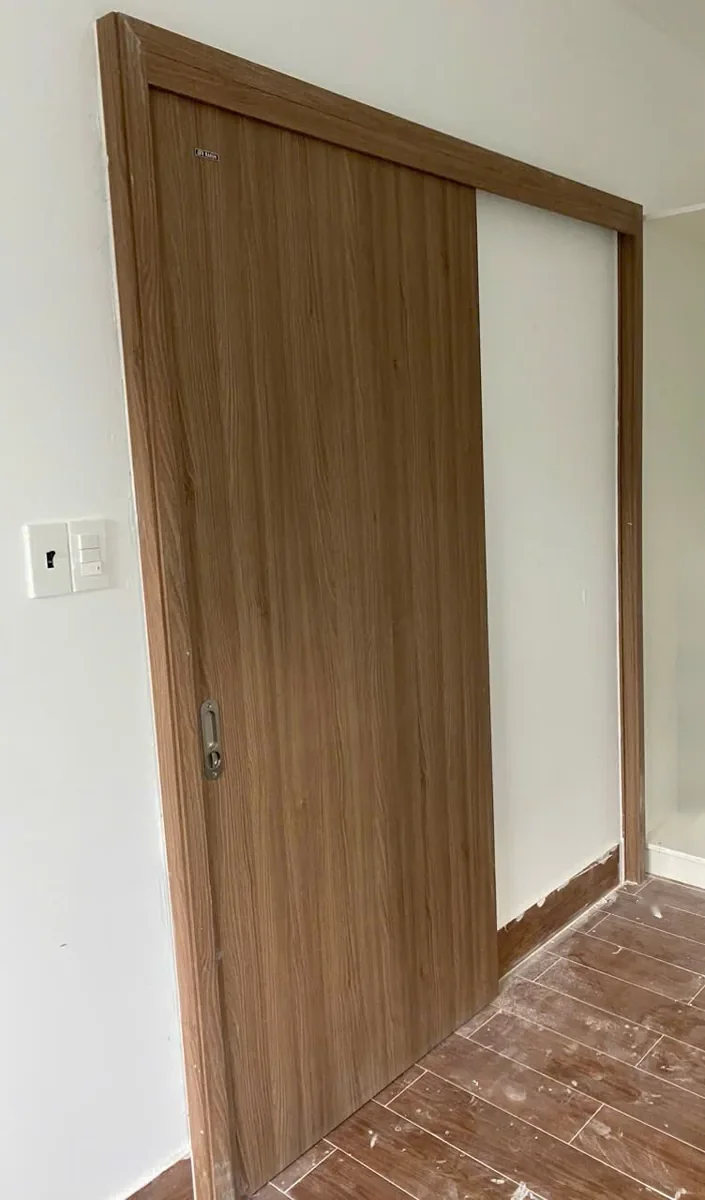 Cửa l&ugrave;a ABS Barun Door v&acirc;n gỗ &oacute;c ch&oacute; mở một phần, c&aacute;nh trượt dọc mảng tường trống b&ecirc;n cạnh &ocirc; cửa