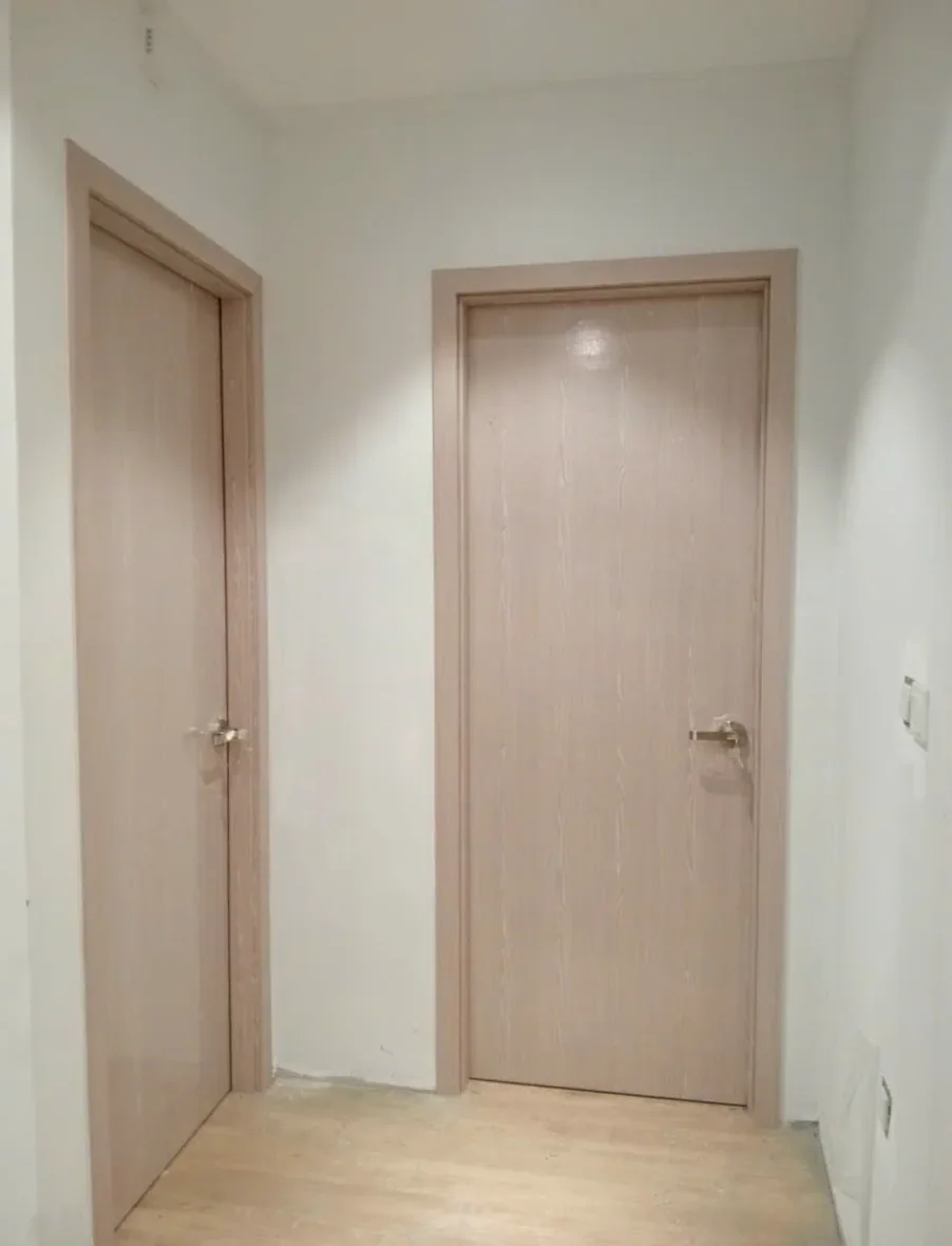 Hai cửa ph&ograve;ng ngủ trơn v&acirc;n gỗ s&aacute;ng c&ugrave;ng m&agrave;u, một cửa b&ecirc;n tường v&agrave; một cửa cuối h&agrave;nh lang, c&ocirc;ng tr&igrave;nh đang ho&agrave;n thiện