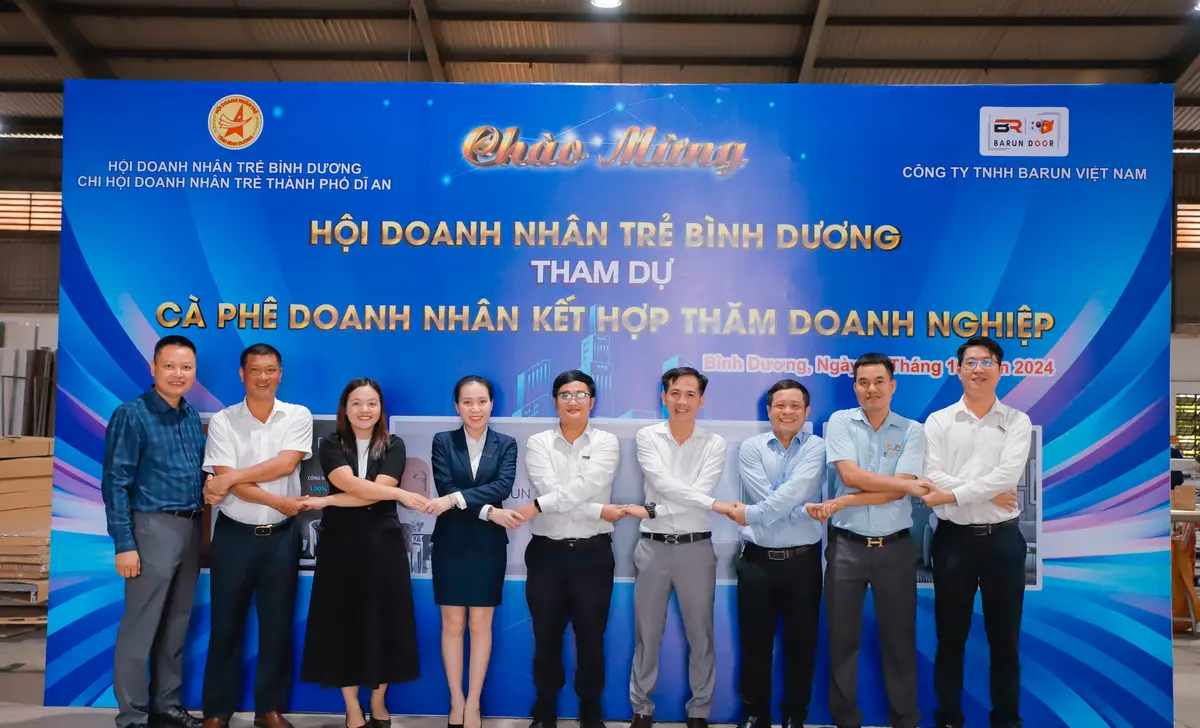 Hội viên Hội Doanh nhân trẻ Bình Dương nắm tay kết nối trước backdrop chương trình tại nhà máy Barun