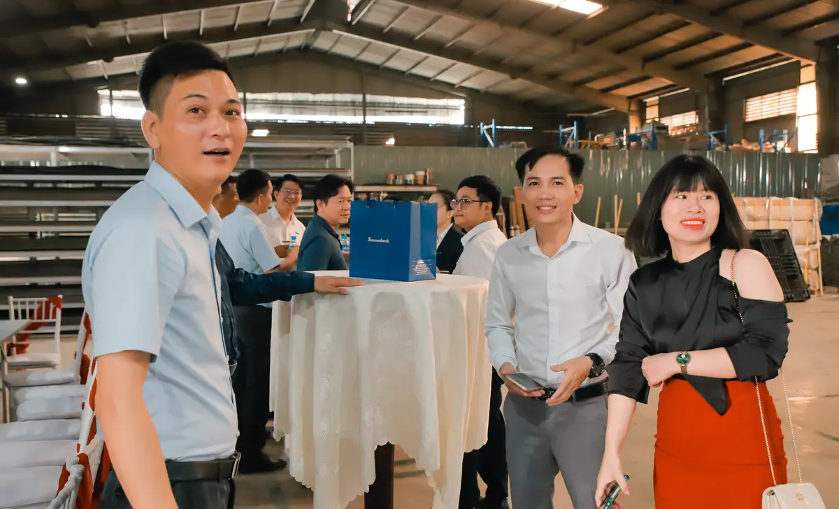 Các doanh nhân trẻ giao lưu bên bàn tiệc đứng trong xưởng sản xuất cửa ABS Barun