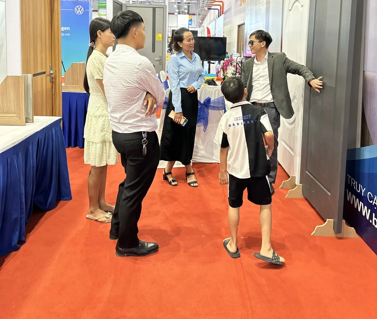 Nhân viên Barun giới thiệu mẫu cửa ABS màu xám cho gia đình khách tham quan tại gian hàng
