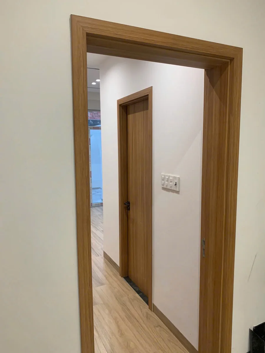 Khung cửa v&agrave; nẹp v&acirc;n gỗ K-1302 của cửa nhựa ABS Barun Door sau lắp đặt, nh&igrave;n qua &ocirc; cửa ra h&agrave;nh lang