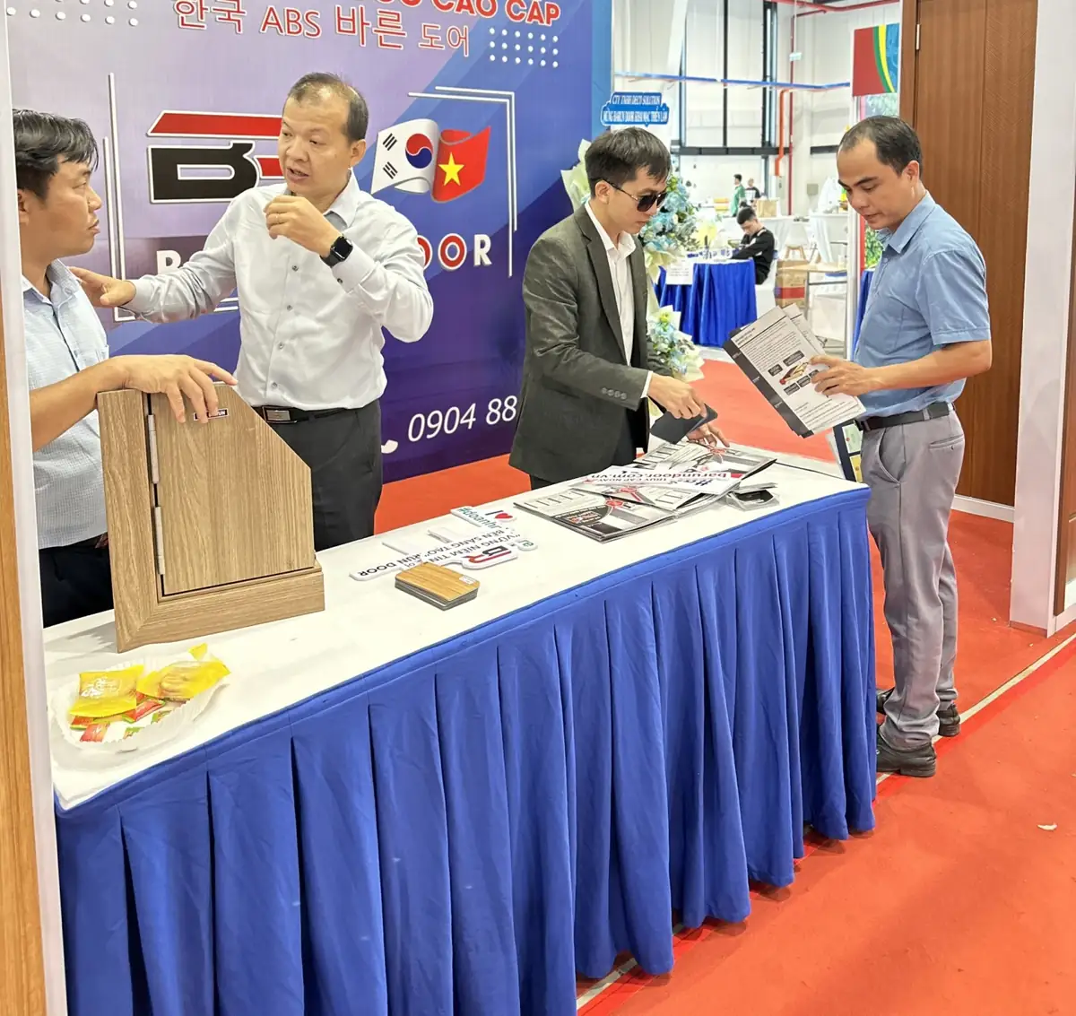 Đại diện Barun trao đổi với khách bên bàn trưng bày mẫu góc cánh khung vân gỗ và catalogue