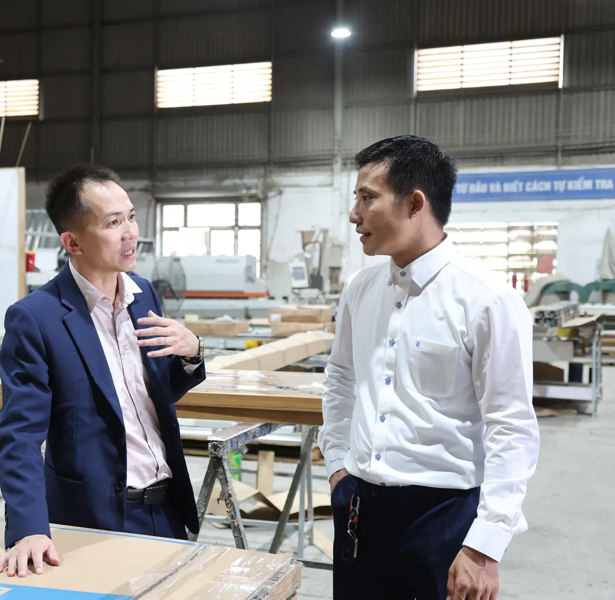 Trao đổi tại xưởng sản xuất cửa nhựa ABS Barun Door, ph&iacute;a sau l&agrave; m&aacute;y d&aacute;n cạnh v&agrave; c&aacute;c c&aacute;nh cửa đang gia c&ocirc;ng